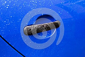 Blue car door handle with rain drops