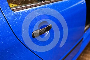 Blue car door handle with rain drops