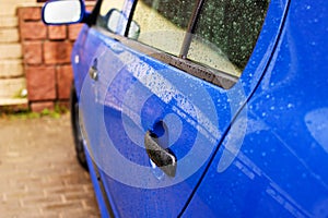 Blue car door handle with rain drops