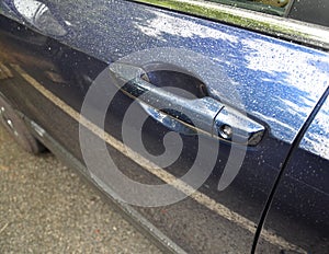 Blue car door handle with water drops and reflection