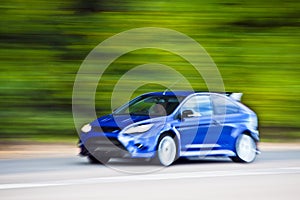 Blue car driving fast on country road