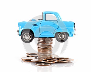 Blue car model jacked by a stack of dollar coins on white background