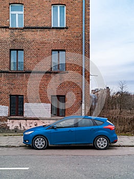 Blue car standing in front of old red brick building