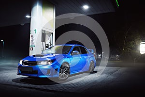 Blue car stay on fuel station in city at night