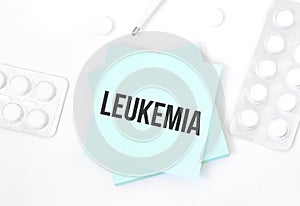 Blue card with text LEUKEMIA on a table with a pills and pencil, medical concept, top view