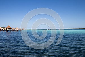 blue and blue Caribbean sea with crystal clear waters and clear sky. a bungalow with a pier in the middle of the lagoon in a coral