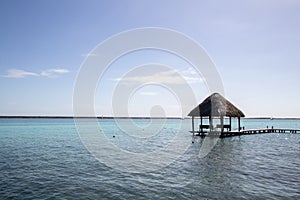 blue Caribbean sea with crystal clear waters and clear sky. a bungalow with a pier in the middle of the lagoon in a coral