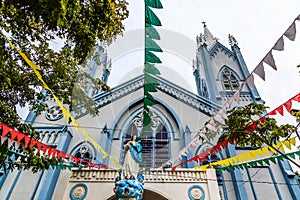 Blue Catholic church decorated with flags and Saint Mary statue