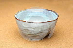 Blue ceramic bowl with clean drink water on sand.