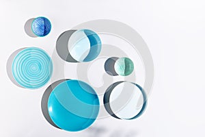 Blue ceramic bowls and plates on white background top view. Colorful ceramic empty dishes with hard shadows.