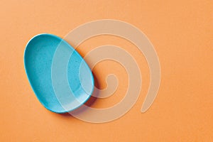 Blue ceramic oval plate on an orange colored background. Modern ceramic crockery, serveware and dinnerware. Blank dinner plate for