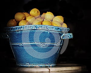 Blue ceramic tub of lemons black background