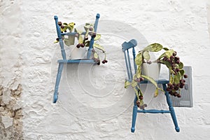 Blue chairs on a white wall with flower pots in the Ostuni Puglia, Italy