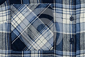 Blue checkered fabric close-up. Part of shirt. Pocket and butto