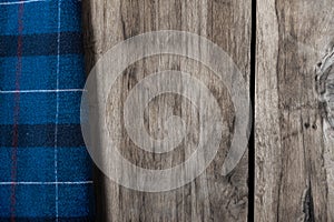 The blue checkered fabric lies against the wooden background. A towel or kitchen napkin on the rough boards or kitchen table