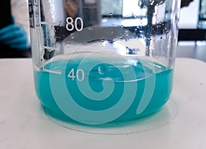 Blue chemical reaction with a liquid substance inside a glass beaker