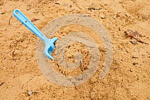 Blue children shovel toy on white sand, plastic play for game. Mound of sand in kindergarden.