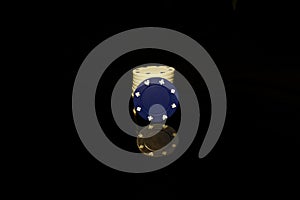 Blue chips stack with a White chip in front isolated on black with reflection