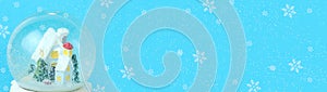 Blue christmas background baner with snow globe with house and fir trees with snowflakes with copy space