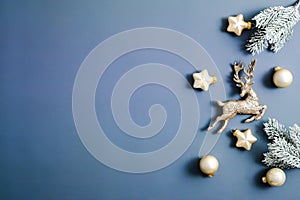 Blue Christmas background. Frame made of gold stars, reindeer, baubles decorations, fir branches. Copy space, flat lay