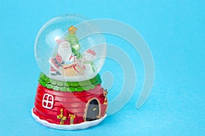 Blue Christmas background with snow globe with Santa, snowman and Christmas tree with copy space