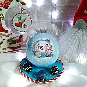 blue Christmas ball with a silver ribbon on a stand with pine cones