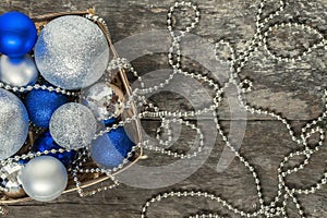 Blue Christmas balls and silver, beads lie in a wooden basket to