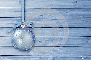 Blue Christmas baubles with curly ribbon on a blue wooden board with copy space. Simple Christmas card