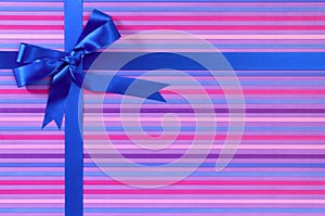 Blue Christmas or birthday gift ribbon bow on candy stripe wrapping paper background