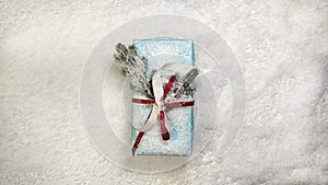 Blue Christmas gift box on a stone background in the snow with ribbons and branches of a Christmas tree. Top view with space for t