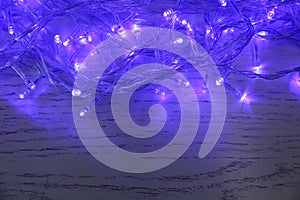 Blue Christmas lights on white wooden background, top view