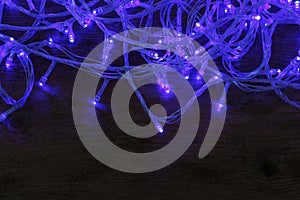 Blue Christmas lights on wooden background. Space for text