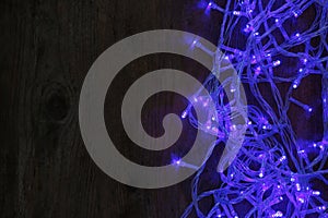 Blue Christmas lights on wooden background. Space for text