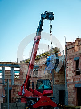 Blue ciment or concrete mixer hanging from red telescopic fork lift truck on a french building site, anti theft photo