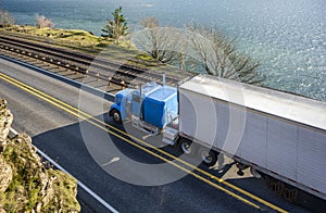Blue classic big rig with reefer semi trailer transporting cargo running on the road along the Columbia River