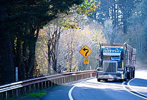 Blue classic semi truck rig with trailer on sunny windy road