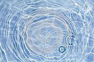 Blue clear water surface texture with splashes and bubbles. Trendy abstract water background. Water waves in sunlight.