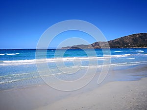 The blue clear water and white sand of a beach in Sardinia