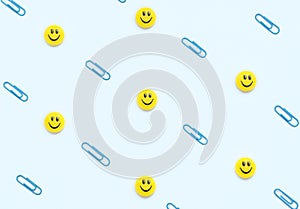 Blue clips and face shaped yellow magnets on white background. School and office supplies, stationary. Back to school concept.