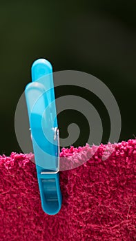 Blue clothes peg used on a pink rag on a clotheslines