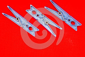 Blue clothes pins on red background concept left side. Open space