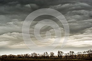 Blue clouds slowly float across the sky, over the newly plowed field, early spring morning