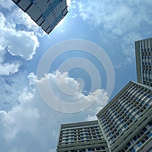 Blue cloudy sky above skycraper building.the sunshine is shy to appear photo