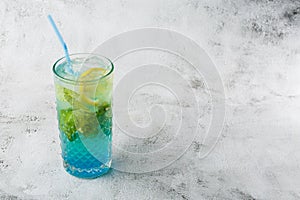 Blue cocktail with ice cubes and slices of lemon and lime. Blue lagoon summer coctail. Iced blue lemonade. Overhead view, copy