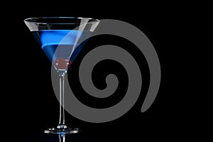 Blue cocktail in martini glass with cherry on black