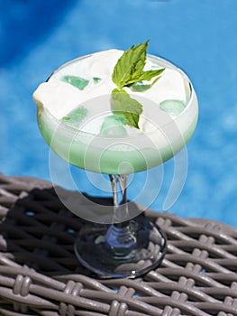 Blue cocktail in a beautiful glass with ice cream and green mint