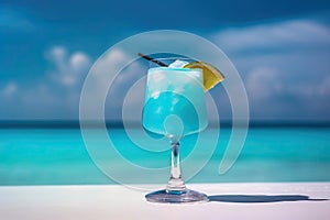 Blue cocktail on the white sand of a paradisiacal beach with the sea in the background. Copy space. Ai generative