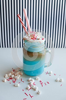 Blue coffee with cream, marshmallow and colorful decoration on a black-and-white background. Milk shake.