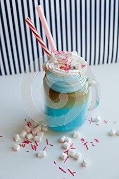 Blue coffee with cream, marshmallow and colorful decoration on a black-and-white background. Milk shake.