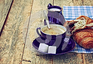 Blue coffee cup, milk jug and croissant with chocolate filling